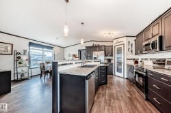 Kitchen featuring stainless steel appliances, a kitchen island with sink, pendant lighting, decorative backsplash, and vaulted ceiling - 