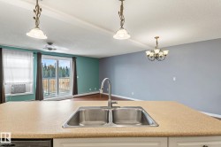 Kitchen with light countertops, a textured ceiling, pendant lighting, open floor plan, and beam ceiling - 