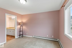 Unfurnished bedroom featuring light colored carpet, multiple windows, a baseboard radiator, and connected bathroom - 