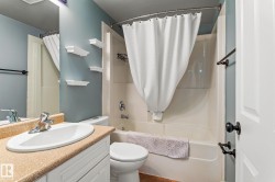 Full bathroom with vanity, shower / tub combo, and dark tile patterned flooring - 