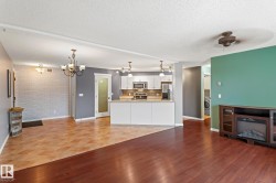 Unfurnished living room with a chandelier, light wood-type flooring, a textured ceiling, washer / dryer, and brick wall - 