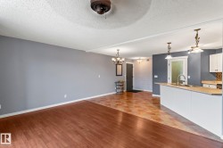 Unfurnished living room featuring a textured ceiling, a chandelier, and light wood-type flooring - 