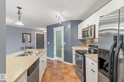 Kitchen with appliances with stainless steel finishes, white cabinets, pendant lighting, light countertops, and a textured ceiling - 