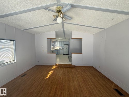 Spacious living area featuring wood-look flooring, a large window with blinds, and a ceiling fan - 4904 51 Avenue, Opal, AB - Indoor Photo Showing Other Room