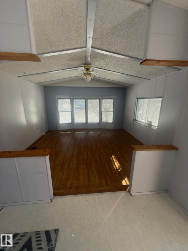 The living area features wood flooring and a ceiling fan, complemented by ample natural light from multiple windows - 4904 51 Avenue, Opal, AB - Indoor Photo Showing Other Room