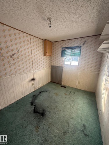 The property features a room with a window, a partial wall cabinet, and wall-mounted shelving - 4904 51 Avenue, Opal, AB - Indoor