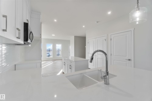 Kitchen featuring white cabinetry, a center island, pendant lighting, recessed lighting, and light stone counters - 262 Chappelle Drive, Edmonton, AB - Indoor Photo Showing Kitchen With Double Sink
