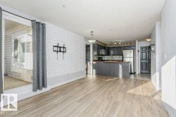 Kitchen featuring open floor plan, light wood-style flooring, dark countertops, stainless steel appliances, and hanging light fixtures - 