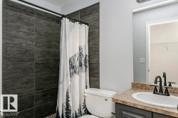 Bathroom featuring tiled shower, vanity, and a spacious closet - 