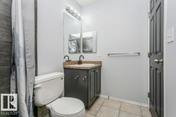 Bathroom featuring vanity, light tile patterned flooring, and curtained shower - 