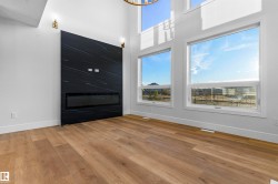 Unfurnished living room featuring light wood-type flooring and a high ceiling - 