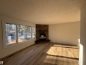 Unfurnished living room with a stone fireplace, wood finished floors, and a textured ceiling - 11744 37 Avenue, Edmonton, AB  - Indoor Photo Showing Living Room With Fireplace 