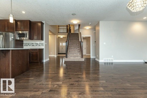 Kitchen featuring dark brown cabinets, hanging light fixtures, open floor plan, a kitchen breakfast bar, and appliances with stainless steel finishes - 3198 Winspear Crescent Sw, Edmonton, AB - Indoor Photo Showing Kitchen