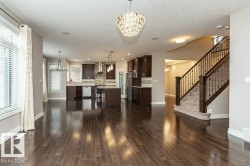 Unfurnished living room with a chandelier, stairs, a textured ceiling, recessed lighting, and dark wood finished floors - 