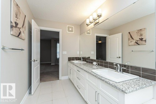 Full bath featuring double vanity, a textured ceiling, light tile patterned floors, and light colored carpet - 3198 Winspear Crescent Sw, Edmonton, AB - Indoor Photo Showing Bathroom