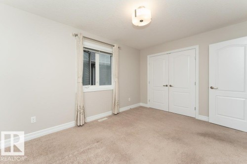Unfurnished bedroom featuring a closet, light carpet, and a textured ceiling - 3198 Winspear Crescent Sw, Edmonton, AB - Indoor Photo Showing Other Room
