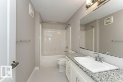 Bathroom with vanity, a textured ceiling,  shower combination, and light tile patterned flooring - 