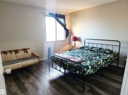 Bedroom with dark wood-style flooring and baseboards - 