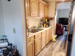 Kitchen with light countertops, light brown cabinetry, backsplash, freestanding refrigerator, and light wood-type flooring - 