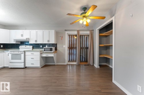 Kitchen with white appliances, white cabinetry, decorative backsplash, light countertops, and a textured ceiling - 4719 47 Avenue, Cold Lake, AB - Indoor Photo Showing Kitchen