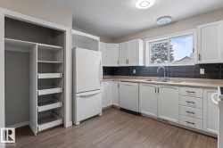 Kitchen with white appliances, a textured ceiling, white cabinetry, tasteful backsplash, and light countertops - 