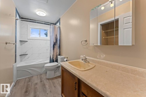 Bathroom with shower / bathtub combination with curtain, light wood finished floors, and vanity - 4719 47 Avenue, Cold Lake, AB - Indoor Photo Showing Bathroom