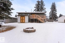 Snow covered rear of property featuring stairway, a deck, a shed, and an outdoor fire pit - 