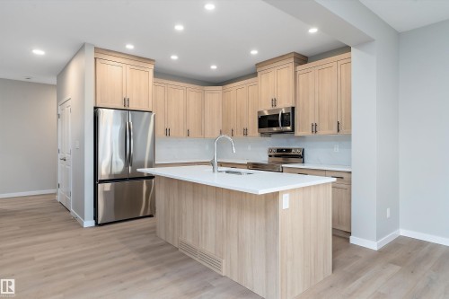Kitchen featuring light brown cabinets, stainless steel appliances, recessed lighting, a kitchen island with sink, and light wood-type flooring - 6320 King Wynd, Edmonton, AB - Indoor Photo Showing Kitchen With Double Sink