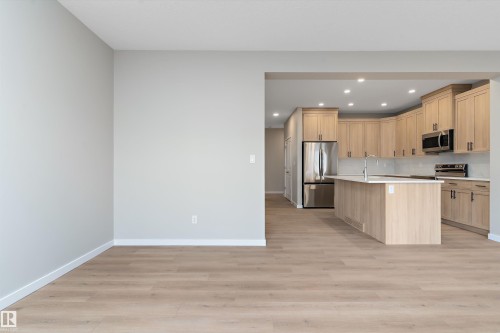 Kitchen with light brown cabinetry, a center island with sink, recessed lighting, stainless steel appliances, and light wood-style flooring - 6320 King Wynd, Edmonton, AB - Indoor Photo Showing Kitchen