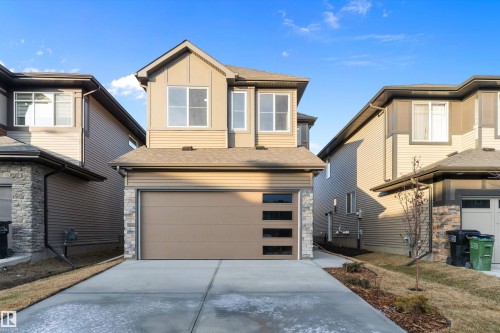 View of front of property featuring roof with shingles, concrete driveway, an attached garage, board and batten siding, and stone siding - 6320 King Wynd, Edmonton, AB - Outdoor With Exterior