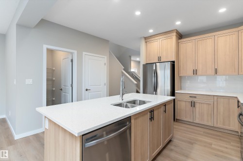 Kitchen featuring light brown cabinetry, stainless steel appliances, light stone counters, light wood-style flooring, and recessed lighting - 6320 King Wynd, Edmonton, AB - Indoor Photo Showing Kitchen With Double Sink
