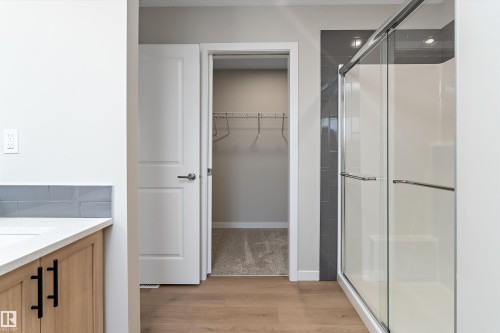 Bathroom with vanity, light wood-type flooring, a spacious closet, and a stall shower - 6320 King Wynd, Edmonton, AB - Indoor Photo Showing Bathroom