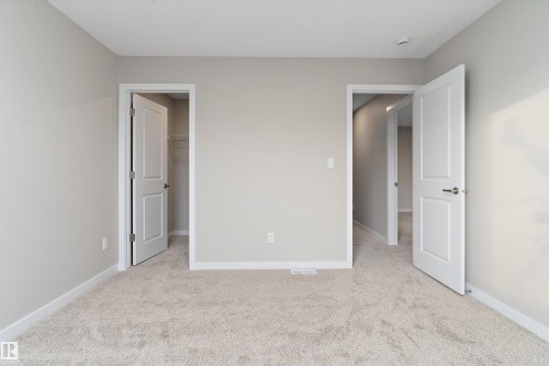 Unfurnished bedroom with light colored carpet and a walk in closet - 6320 King Wynd, Edmonton, AB - Indoor
