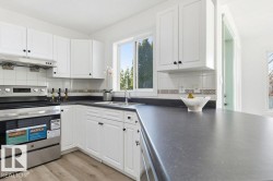 Kitchen featuring appliances with stainless steel finishes, white cabinets, under cabinet range hood, backsplash, and dark countertops - 
