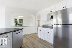 Kitchen featuring appliances with stainless steel finishes, white cabinetry, dark countertops, light wood finished floors, and a textured ceiling - 