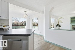Kitchen with stainless steel dishwasher, dark countertops, pendant lighting, white cabinetry, and a textured ceiling - 