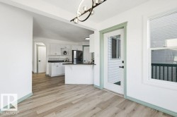 Kitchen with white cabinets, dark countertops, a peninsula, freestanding refrigerator, and open shelves - 