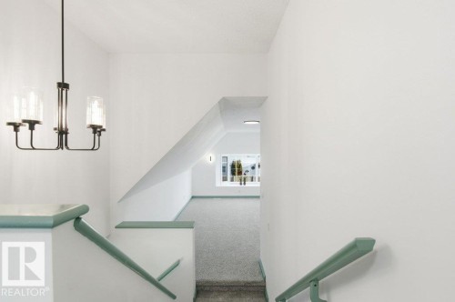 Stairs with carpet flooring and a chandelier - 1112 118A Street Nw, Edmonton, AB - Indoor Photo Showing Other Room