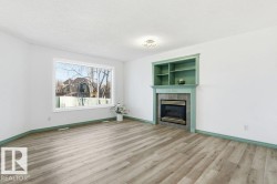 Unfurnished living room with a textured ceiling, a fireplace, light wood finished floors, and built in shelves - 