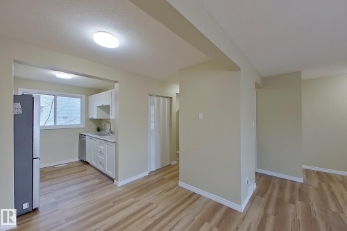 Kitchen with white cabinets, light countertops, stainless steel appliances, light wood finished floors, and a textured ceiling - 112 Dickinsfield Court Nw, Edmonton, AB - Indoor Photo Showing Other Room