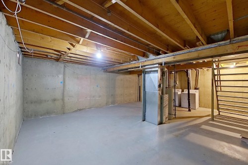 Unfinished basement featuring heating unit, stairway, and washing machine and clothes dryer - 112 Dickinsfield Court Nw, Edmonton, AB - Indoor Photo Showing Basement