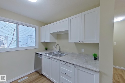 Kitchen featuring light countertops, white cabinets, dishwasher, and light wood-style flooring - 112 Dickinsfield Court Nw, Edmonton, AB - Indoor Photo Showing Kitchen With Double Sink