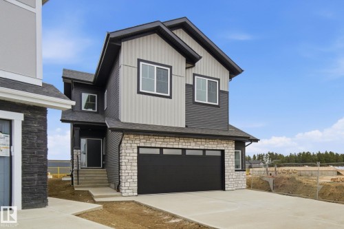 View of front of home with stone siding, a garage, driveway, and roof with shingles - 3309 Chernowski Way, Edmonton, AB - Outdoor
