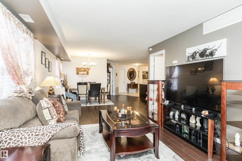 Living room with dark wood finished floors, a chandelier, and a textured ceiling - 107 10118 106 Avenue, Edmonton, AB - Indoor Photo Showing Living Room