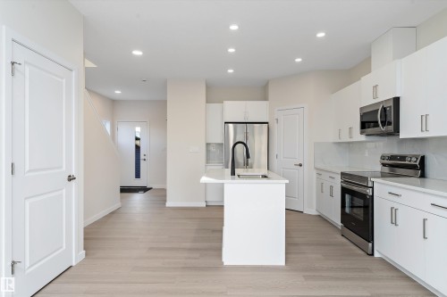 Kitchen featuring stainless steel appliances, an island with sink, decorative backsplash, recessed lighting, and white cabinetry - 823 Rowan Close, Edmonton, AB - Indoor Photo Showing Kitchen With Upgraded Kitchen