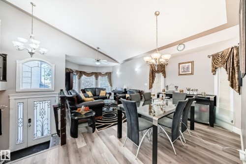 Dining space featuring a chandelier, light wood-type flooring, high vaulted ceiling, and a ceiling fan - 1715 69 Street, Edmonton, AB - Indoor Photo Showing Dining Room