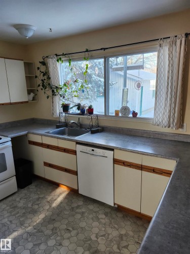 Kitchen featuring white cabinetry, white appliances, light flooring, open shelves, and dark countertops - 11212 134 Avenue, Edmonton, AB - Indoor Photo Showing Kitchen With Double Sink