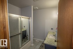 Bathroom featuring vanity, light tile patterned floors, and a shower with shower door - 