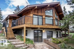 Wood-sided exterior with expansive upper-level decking featuring black metal railings - 