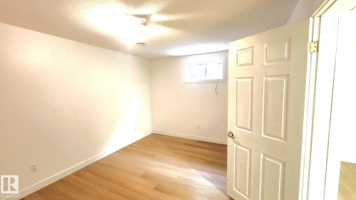 Below grade area with a textured ceiling and light wood-style flooring - 11516 133A Avenue, Edmonton, AB - Indoor Photo Showing Other Room